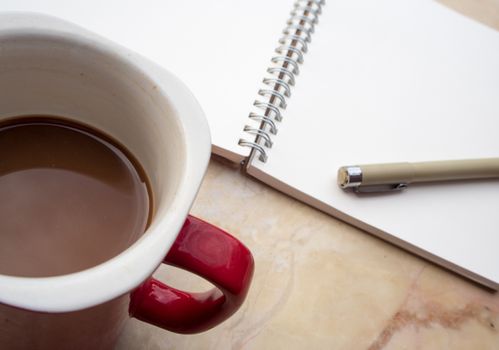The blank page of a spiral notebook and coffee cup