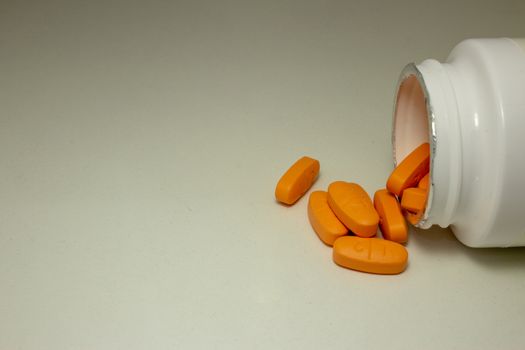 Pills spread over a white table, next to the open bottle