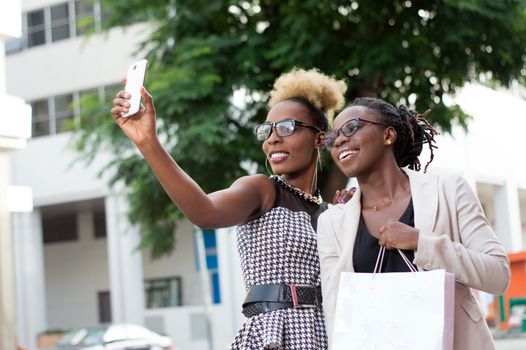 Two happy businesswomen taking selfie by smart phone outside