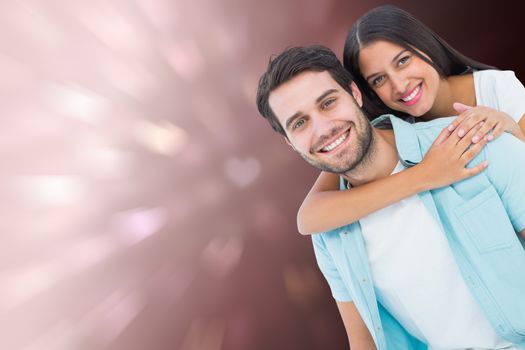 Happy casual man giving pretty girlfriend piggy back against valentines heart design