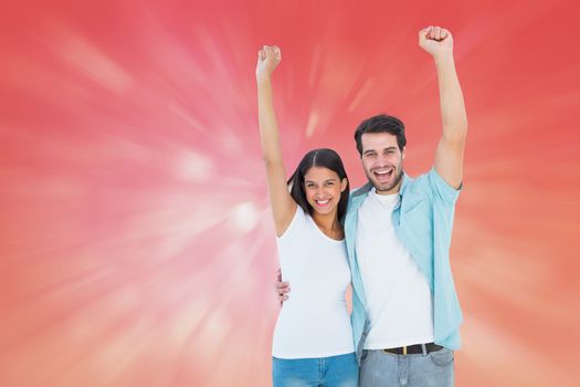 Happy casual couple cheering together against red abstract light spot design