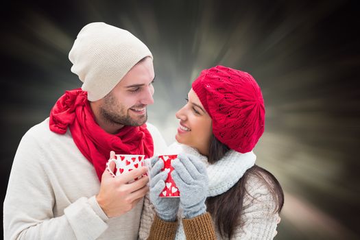 Winter couple holding mugs against black abstract light spot design