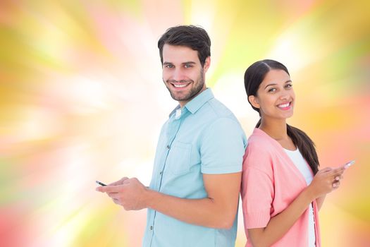 Happy couple sending text messages against girly pink and yellow pattern