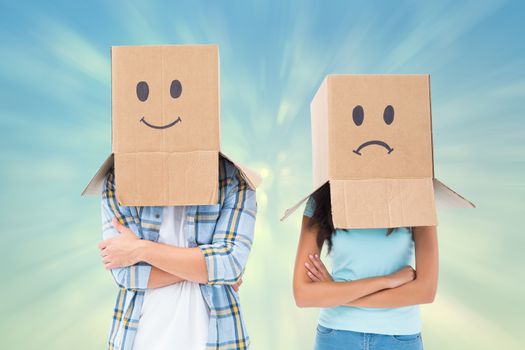 Young couple wearing sad face boxes over head against blue abstract light spot design