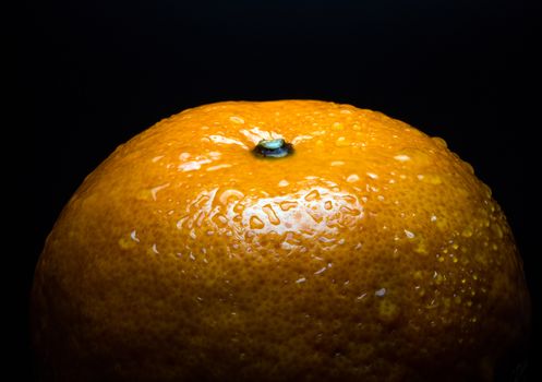 Close-up of Water droplet on glossy surface of freshness orange on black background