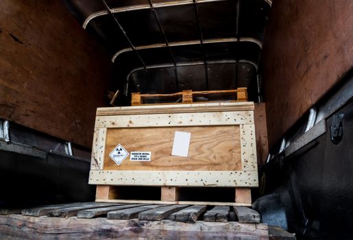 Radiation warning sign on the Hazardous materials transport label Class 7 at the wooden box package in the container of transport truck