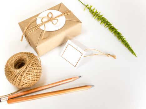 Brown gift box wrapped in kraft paper and rustic hemp cord spool as natural rustic style with paper and pencil for write your note