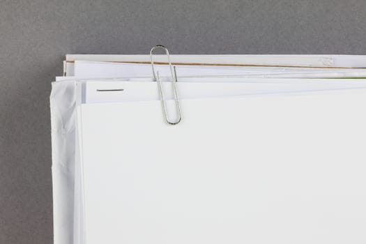A bundle of work papers with paperclip on grey background