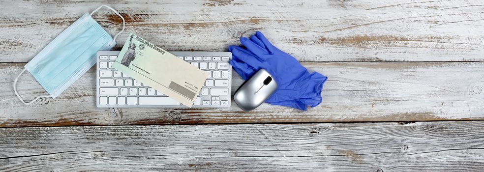 Economic impact stimulus check on white wooden desktop with personal protection and computer equipment 