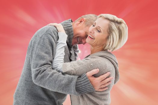 Happy mature couple in winter clothes against red abstract light spot design