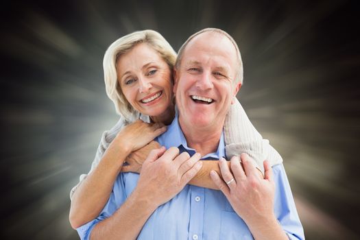 Happy mature couple embracing smiling at camera against black abstract light spot design