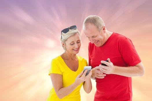 Happy mature couple looking at smartphone together against pink abstract light spot design