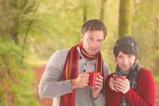 Couple both having warm drinks against peaceful autumn scene in forest