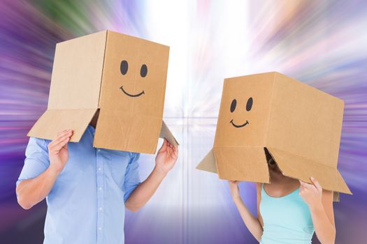 Couple wearing emoticon face boxes on their heads against glittering screen in urban setting