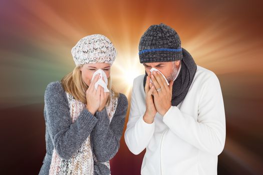 Sick couple in winter fashion sneezing against sunrise over mountains