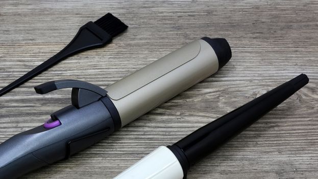 Hair style, ceramic Curling iron and hair brush on wooden table