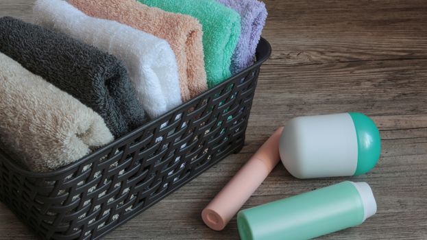 colorful towels and cosmetics in a basket on a wooden table