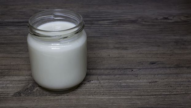Greek yogurt, milk in a glass jar on a wooden table, detox, diet