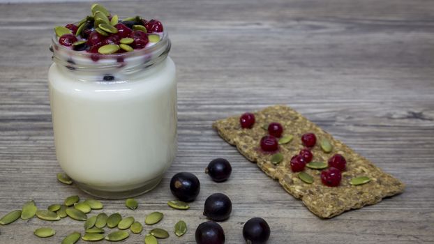 Greek yogurt, milk, smoothies, blueberries and currants in a glass jar on a wooden table, detox, diet