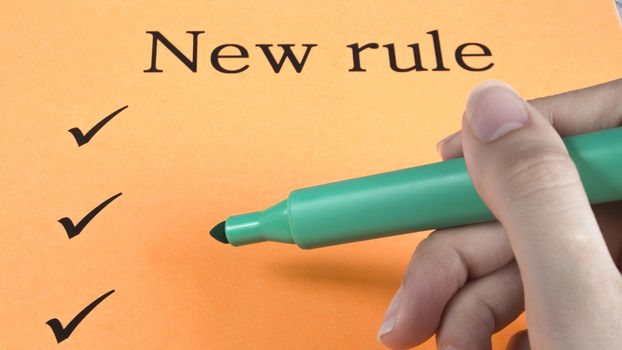 Hand writes marker on orange paper, text, message, new rules, art, study, creativity, design