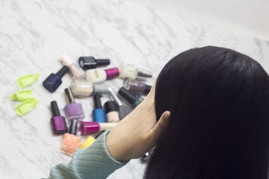 Young woman chooses nail polishes, beauty and fashion, difficulty of choice, dilemma, Spa salon at home,