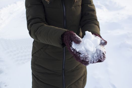 Young woman holding snow in her hands in mittens, winter, fun, joy, sports, recreation, children