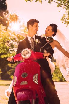 Portrait of a newlywed couple sitting on scooter in the park