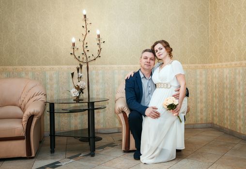 couple of lovers posing sitting on chair in the hall of prefecture at marriage