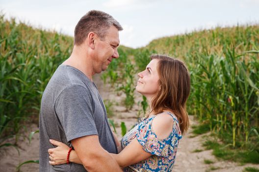 couple of lovers look at each other smiling at the corn field on a sunny summer day