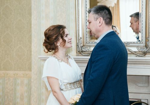 couple of lovers smiling look at each other standing in the hall of prefecture at marriage