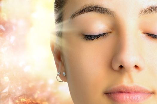 Extreme Close up face shot of young woman with eyes closed.Girl doing mental exercise against bright background with light beam.