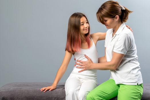 Close up portrait of child at osteopathic therapy session. Female physiotherapist manipulating thorax of little girl.