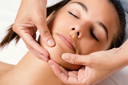 Close up top view portrait of woman at beauty treatment session. Therapist applying cream on chin.