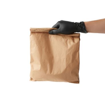 hand in a black latex glove holds a full paper bag of brown craft paper, the concept of remote and contactless food delivery, safe receipt of orders, white background