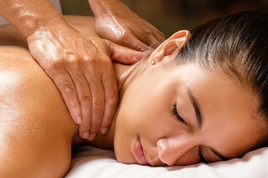 Close up of woman enjoying revitalizing shoulder and neck massage in spa.