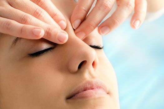 Extreme close up of therapist doing reiki on young woman.Fingers applying pressure between eyes.