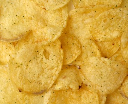 heap of round yellow fried potato chips with dill, food with spice, top view