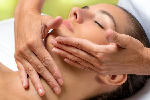 Close up portrait of woman having facial treatment in spa.Hands applying neck cream with continuous smooth movements on woman.