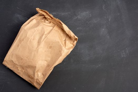 brown paper bag on a black background, top view, place for an inscription