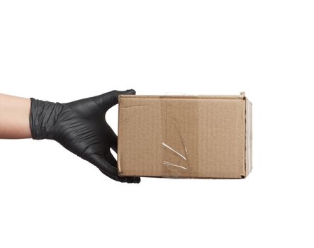 female hand in black latex glove holds a cardboard box of brown kraft paper on a white background, safe and contactless delivery of on-line orders during epidemics