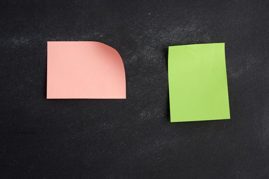 blank pink and green paper sticker glued on a black board, place for an inscription, close up