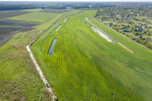 Land improvement or land amelioration concept, drone flying over narrow irrigation or drainage channels on rye or wheat field. Illustration of agriculture in the zone of risky agriculture.