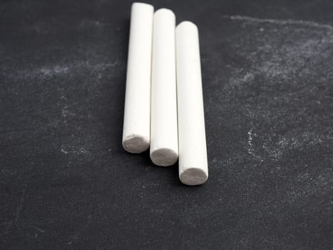 three white chalk on a black surface, close up