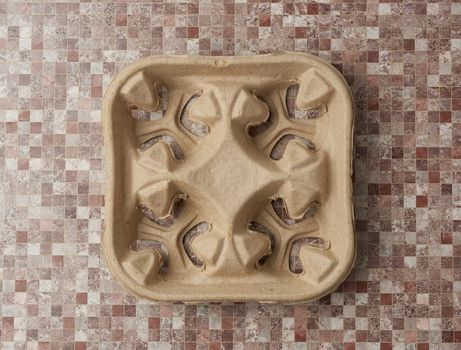 empty paper tray for drinks in takeaway cups on four cups on brown background, top view