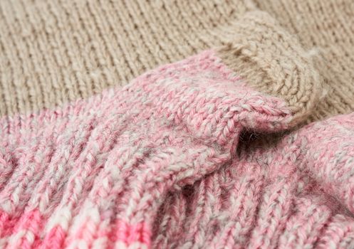 fragment of knitted socks from beige and pink woolen thread, close up