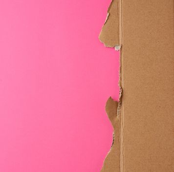 torn edges of corrugated brown cardboard paper on a pink background. place for inscription.