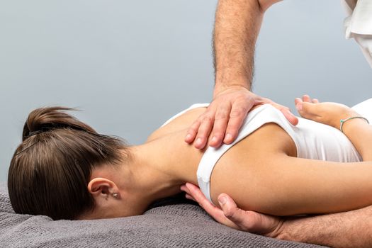 Close up detail of mail physiotherapist applying pressure on female shoulder blade. 