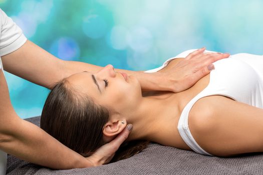 Close up of young female patient receiving physical therapy.Therapist manipulating back of head and chest against colorful background.