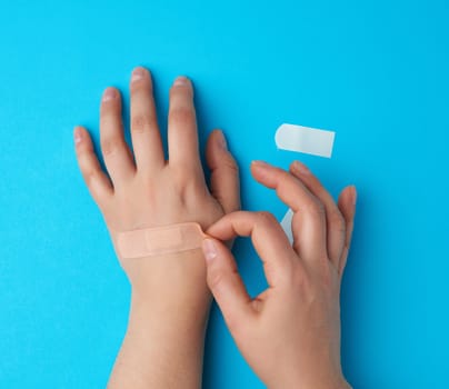 beige patch glued on the palm, assistance, blue background, top view