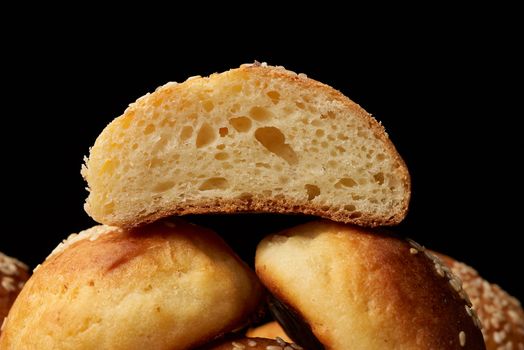 baked round bun with sesame seeds, black background, home baking